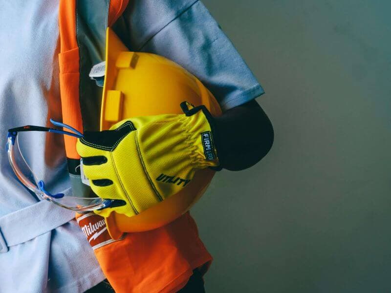 Construction worker holding hard hat and safety gear